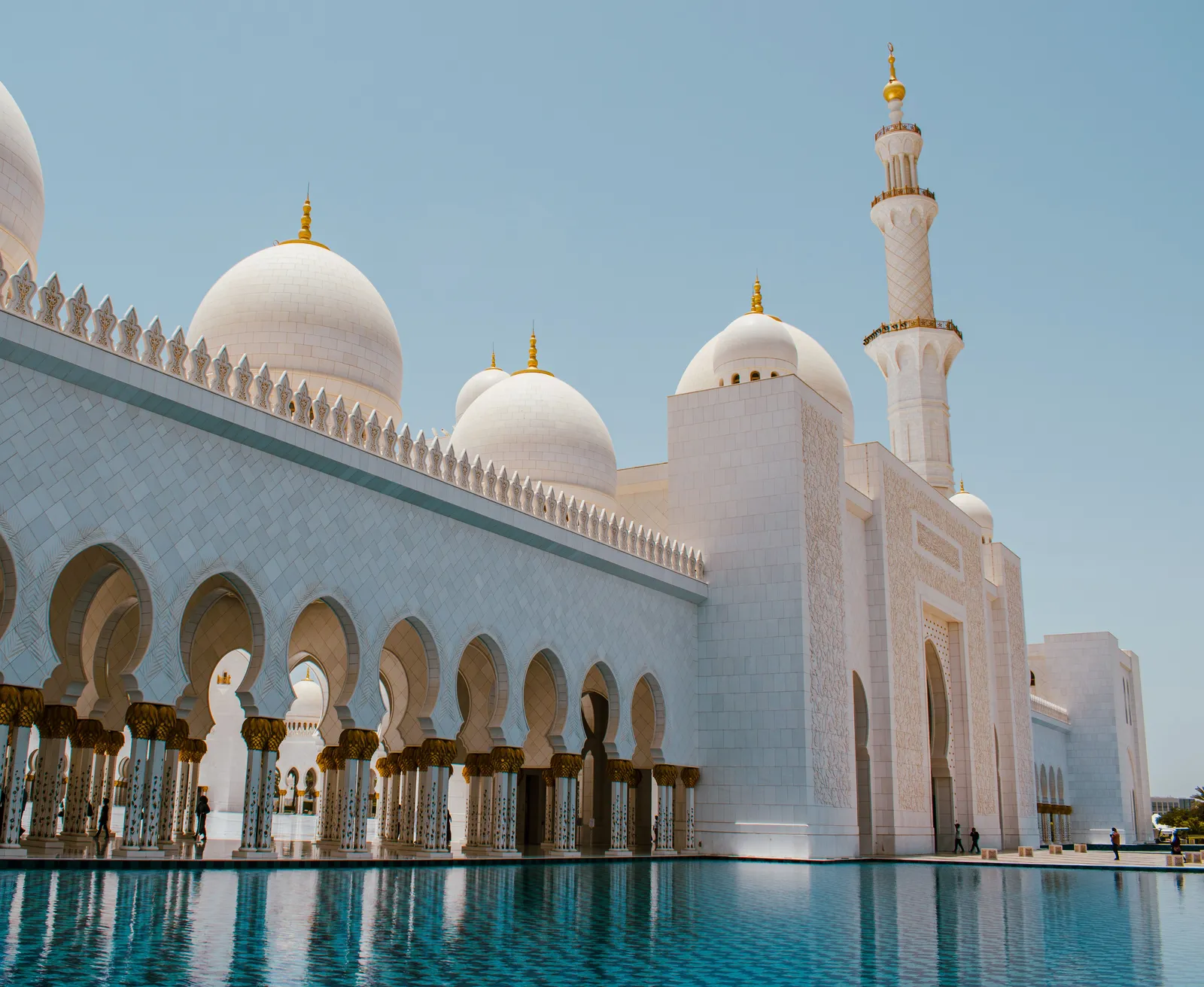 The white marble domes, minaret and arcade of Sheikh Zayed Grand Mosque reflected in the pool, Abu Dhabi