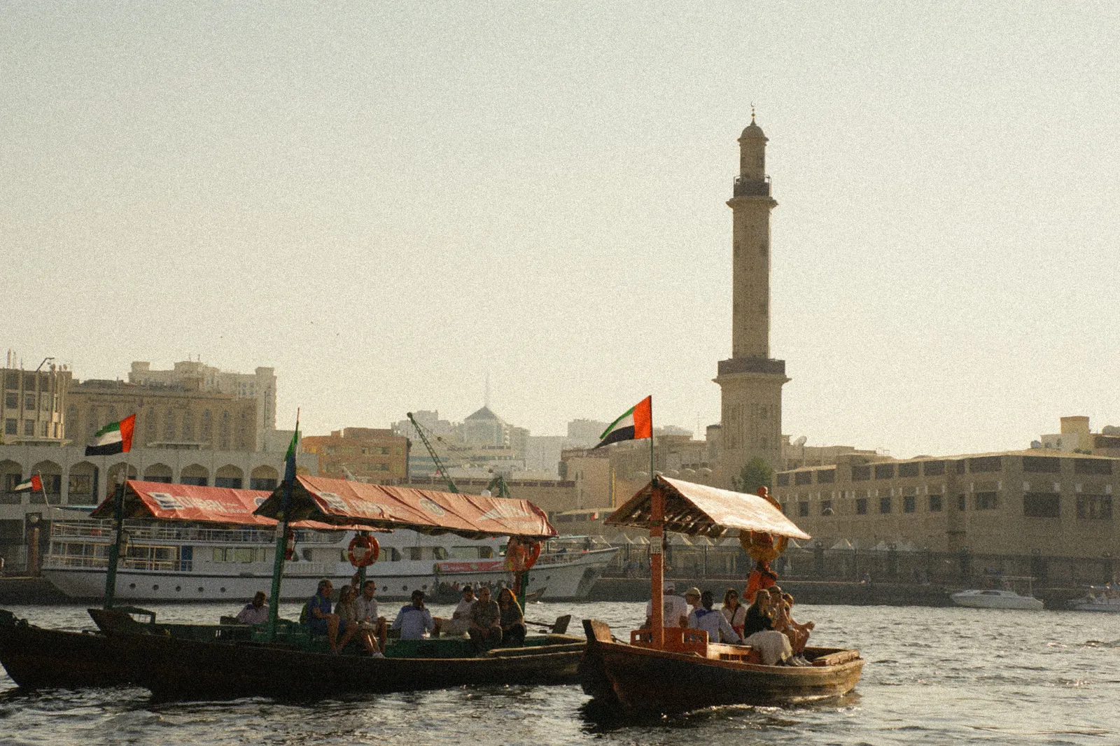 Wooden abras moored along the Dubai Creek waterfront with a minaret behind