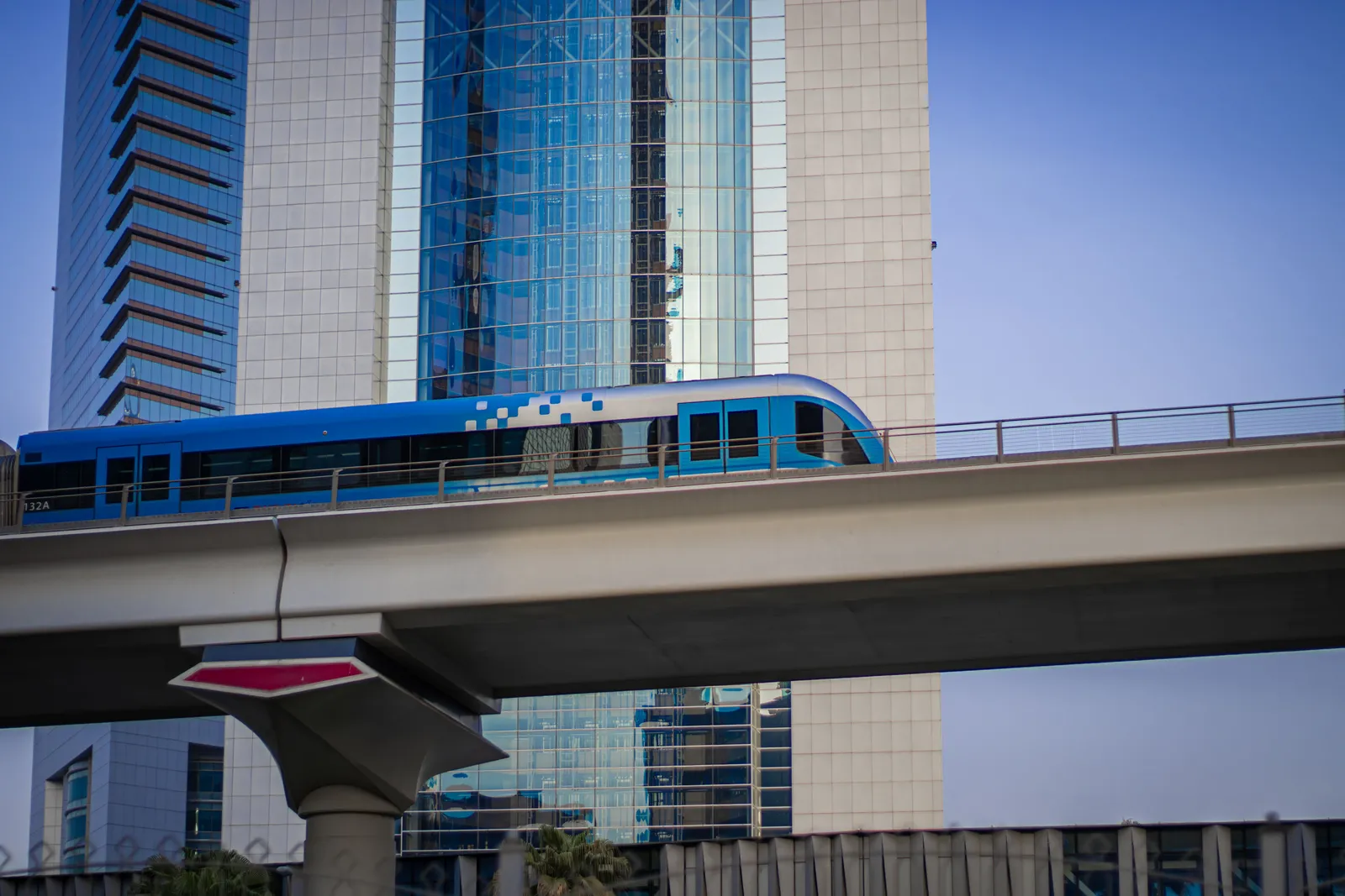 A modern metro train arriving at an elevated station in Dubai, United Arab Emirates