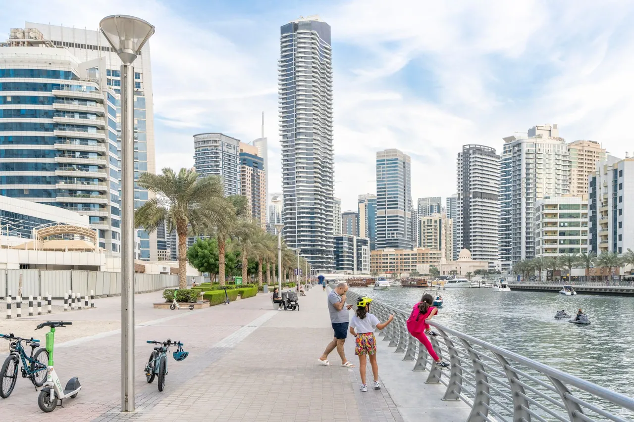 The Marina Walk promenade lined with cafes and moored boats in Dubai Marina
