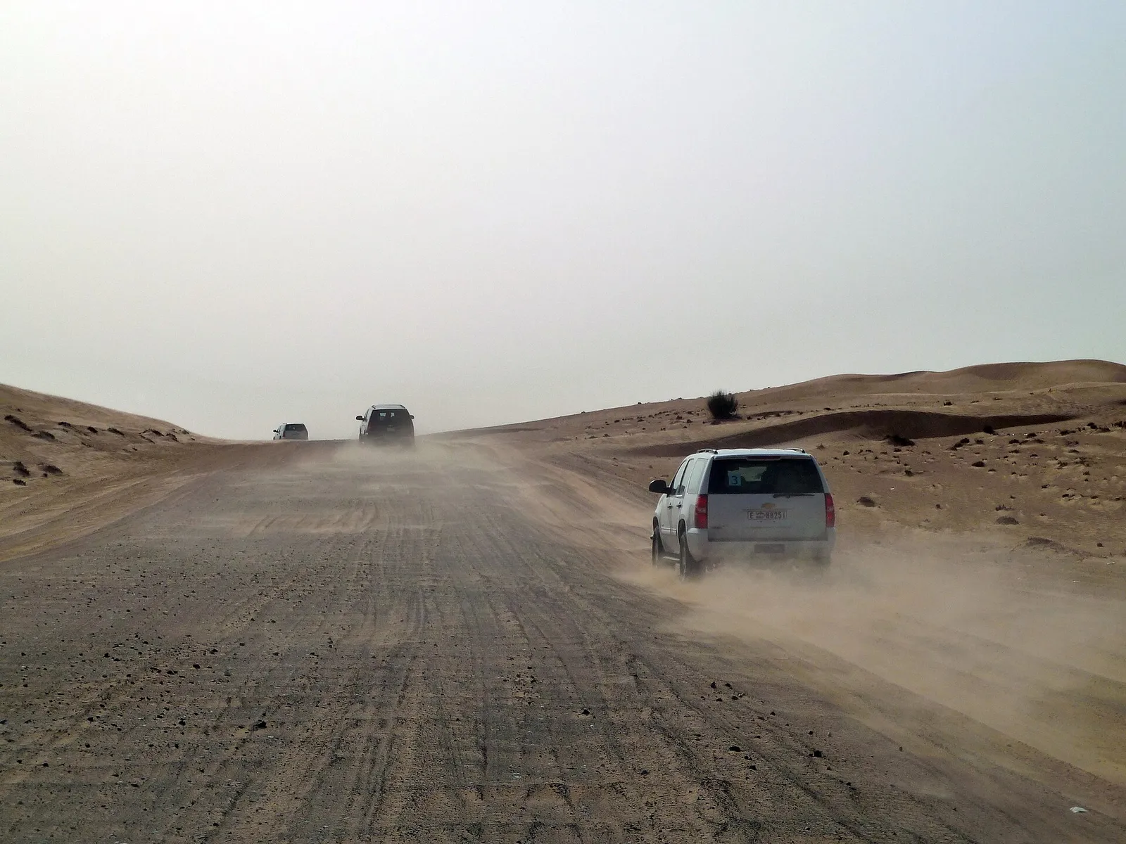 A four wheel drive driving through desert dust outside Dubai, United Arab Emirates