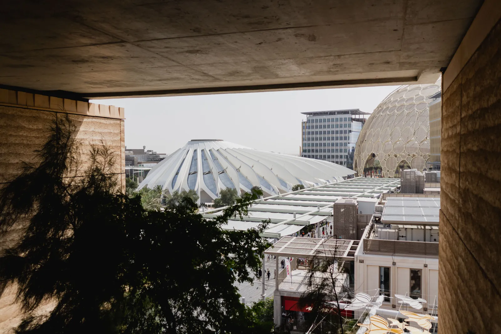 A family walking through an open plaza with the Al Wasl Dome visible in the background at Expo City Dubai