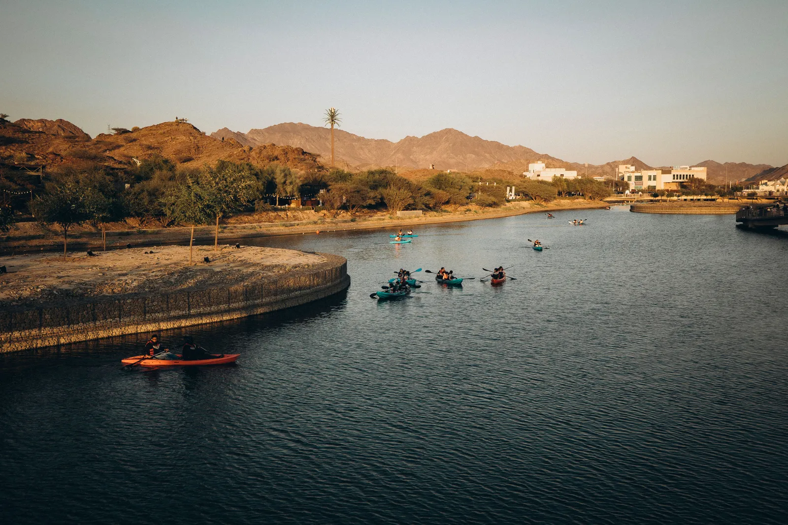 Kayakers out on the water at Hatta Dam with bare rocky mountains behind them