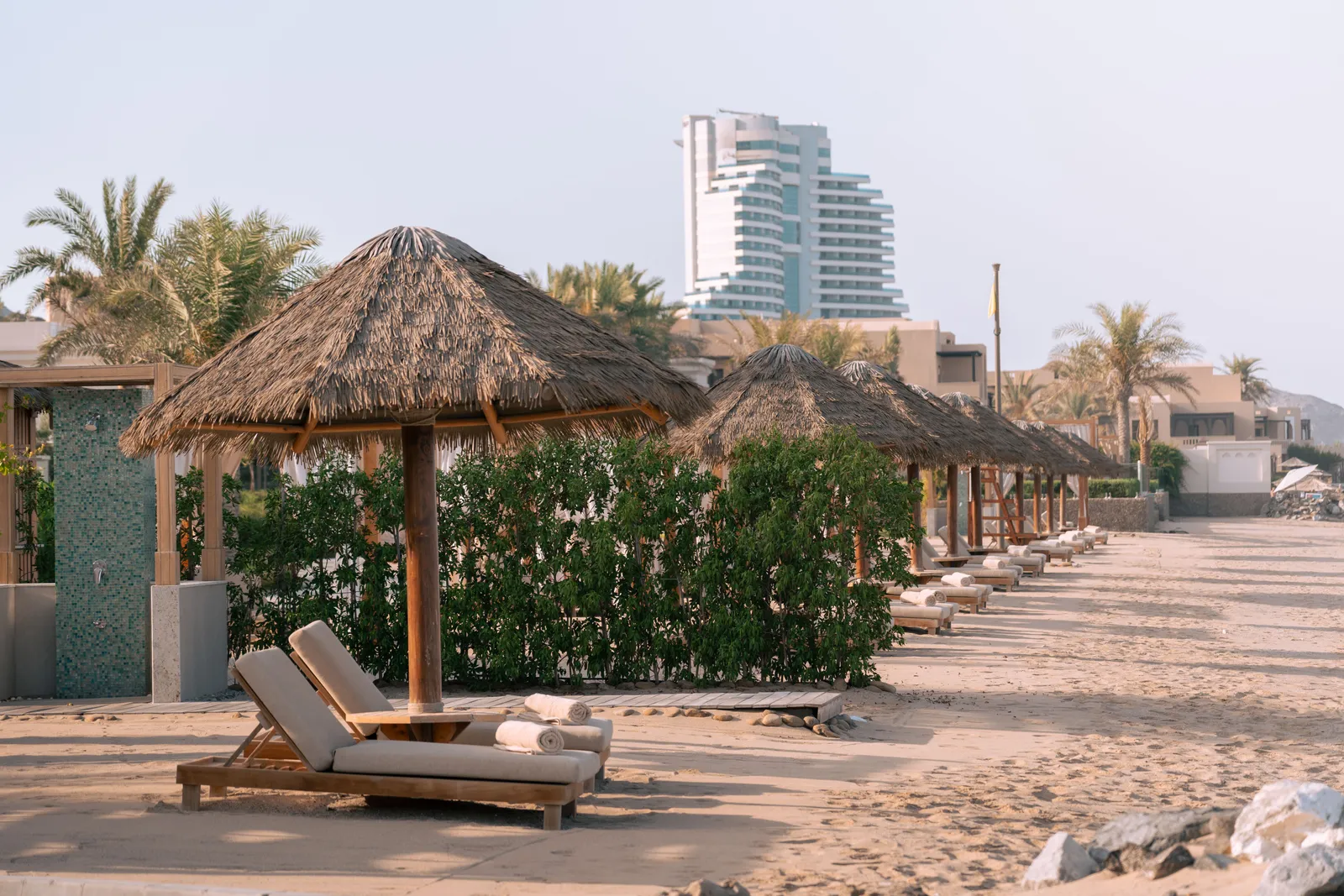 Sun loungers and umbrellas on the open sand at La Mer beach in Dubai with restaurant terraces behind