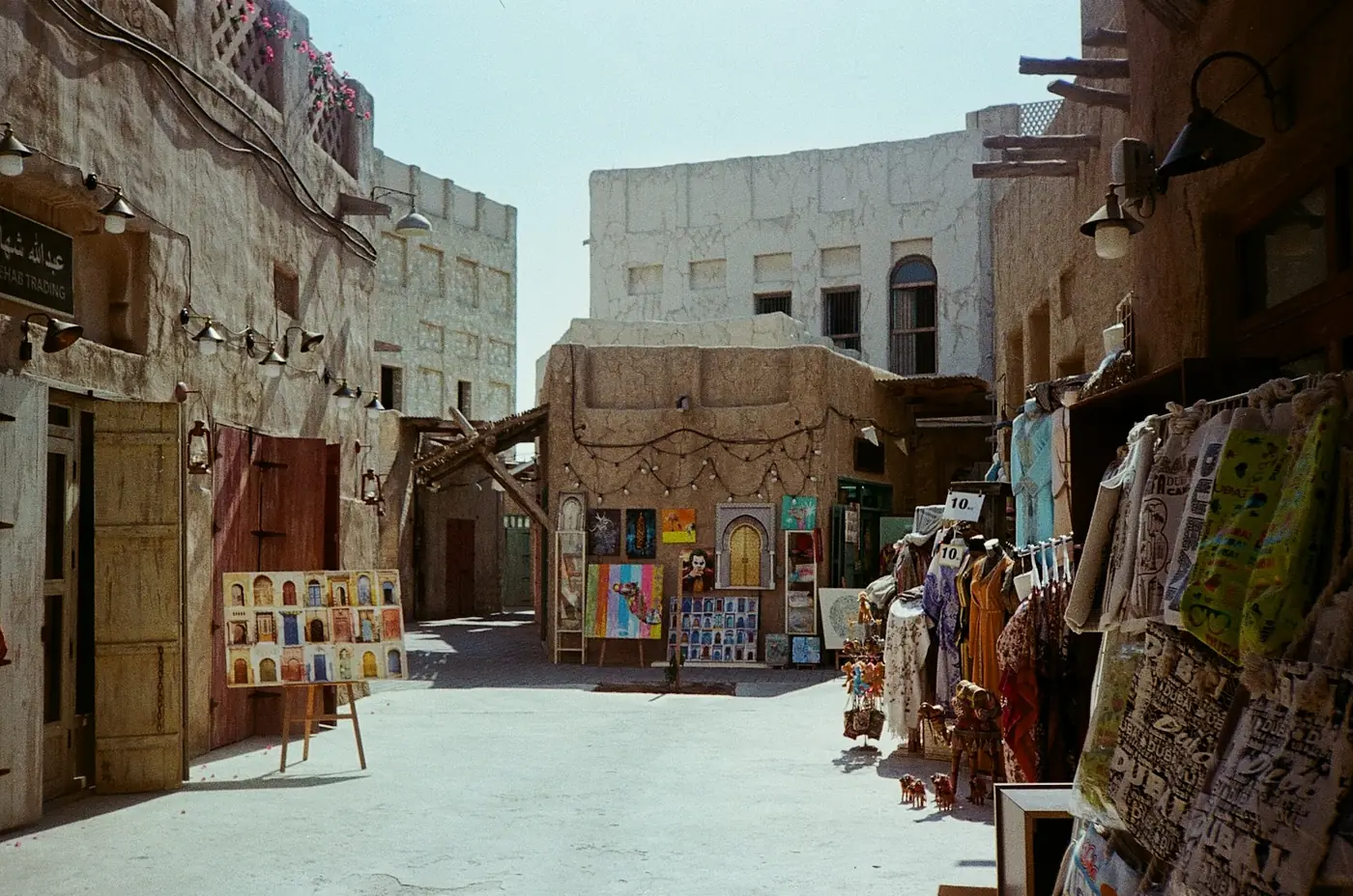 A quiet lane of traditional coral-stone buildings and souvenir shopfronts in old Dubai, United Arab Emirates