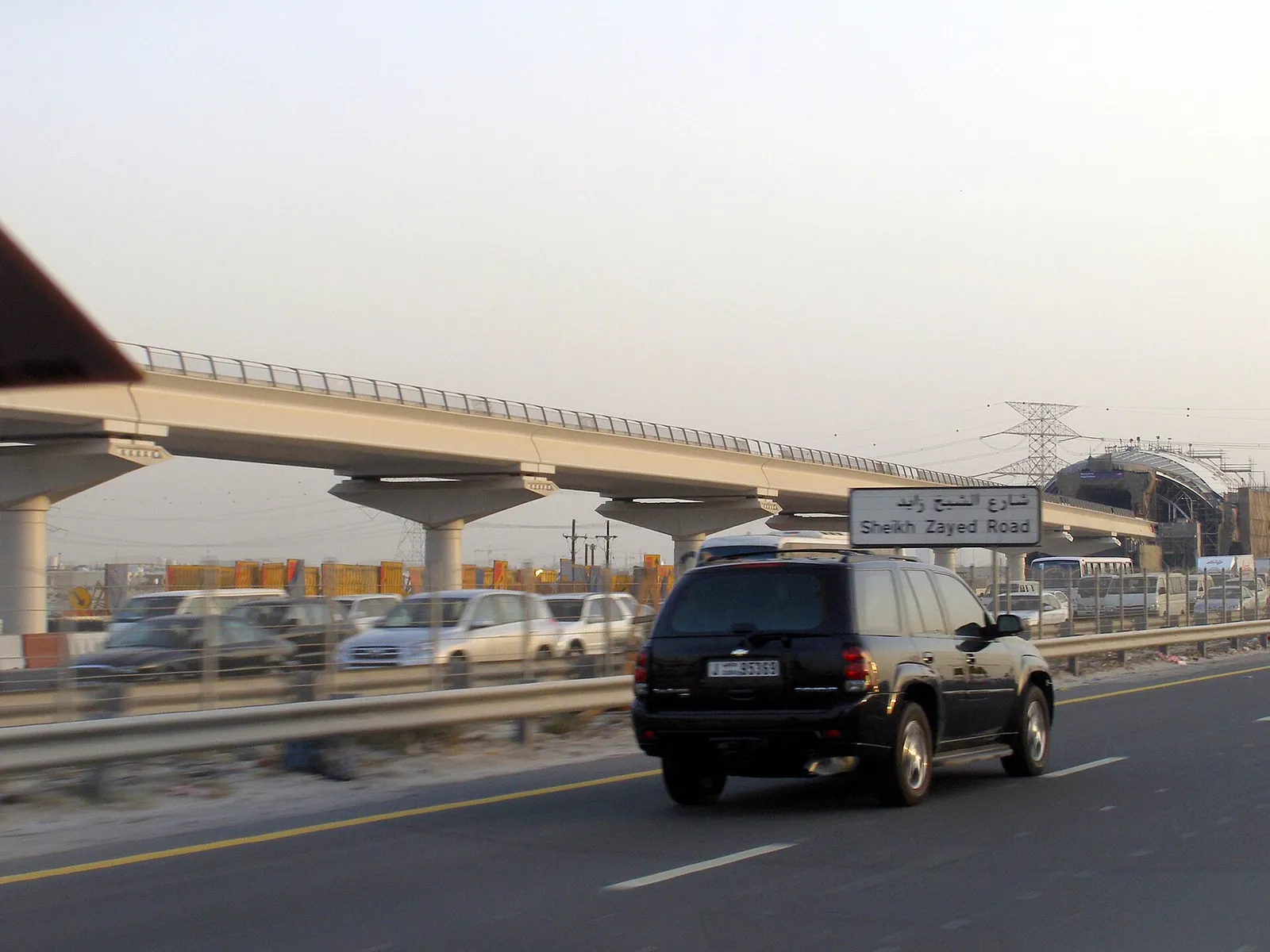 The elevated Dubai Metro viaduct running beside a main road in Dubai, United Arab Emirates