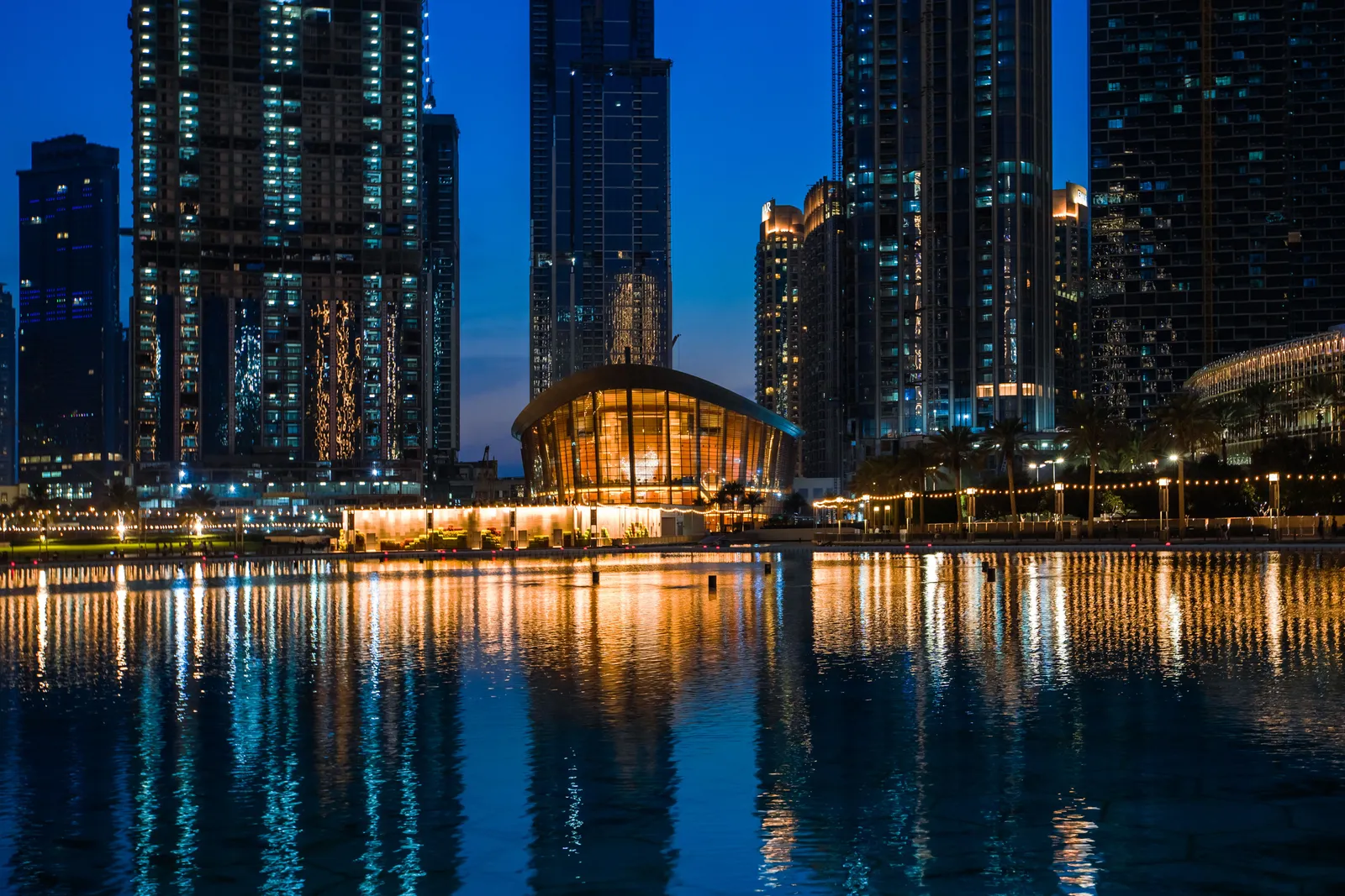 The dhow shaped exterior of Dubai Opera at dusk with the Burj Khalifa rising behind it in Downtown Dubai