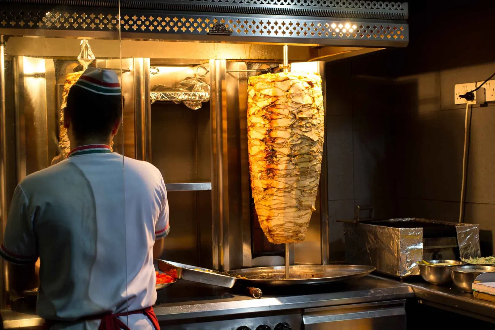 A cook slicing meat from a shawarma spit at a counter in Dubai, United Arab Emirates