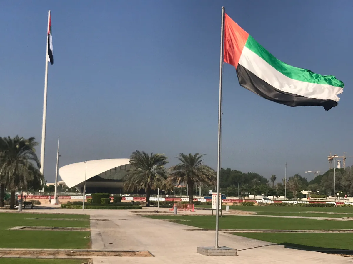 The Emirati flag before a museum roof shaped like a scroll