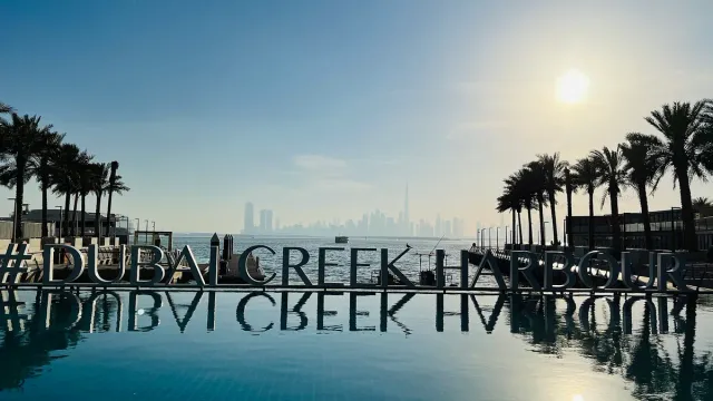 Giant letters at the water edge reflected in a pool with a skyline on the horizon