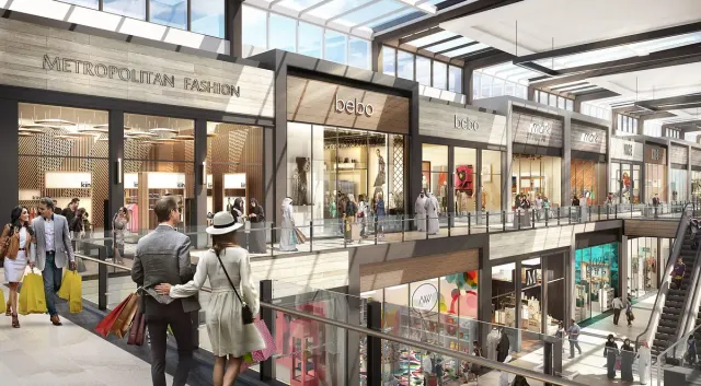 A covered mall concourse with fashion stores on two levels and bright lighting