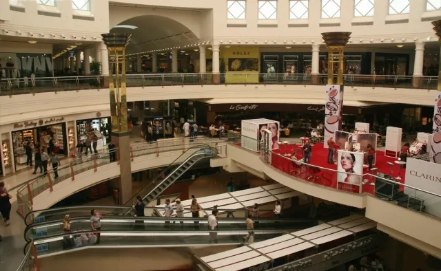 A mall atrium with curved railings on two levels and a red centrepiece display