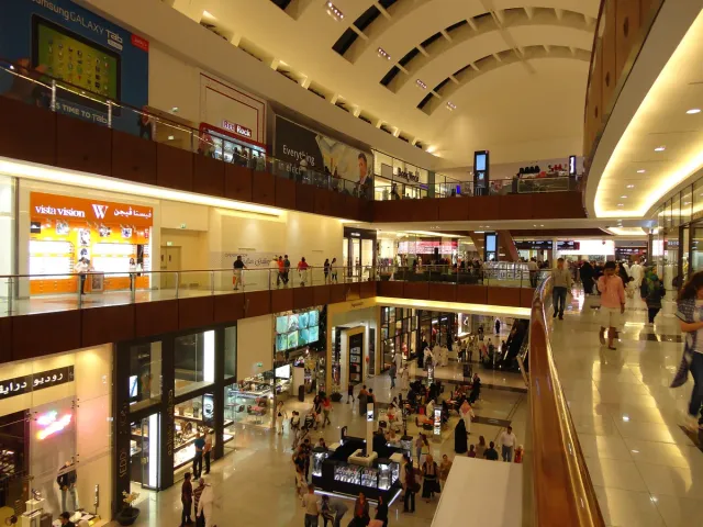 A wide mall level with lit shop windows on both sides and a curved ceiling