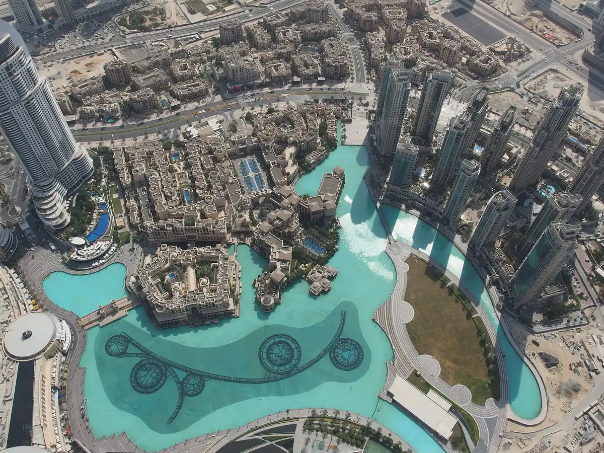 A view straight down onto a turquoise lake and the towers of the city centre