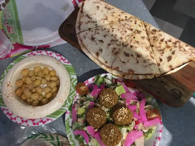 A tray with hummus, falafel balls, chopped vegetables and flatbread