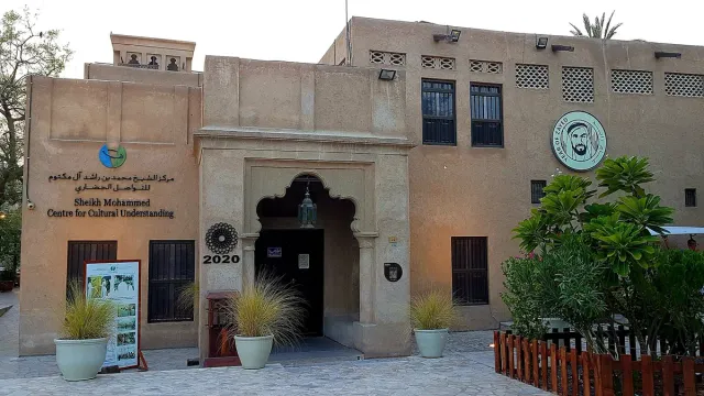 The plastered facade of a traditional house with a wooden door, signs and potted plants
