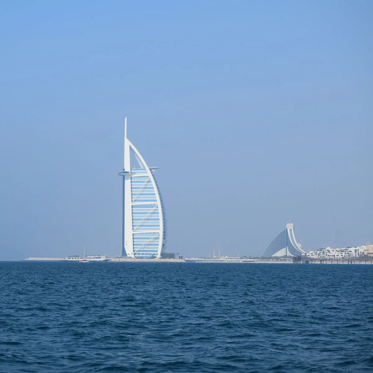 A sail shaped tower on an artificial island by the sea
