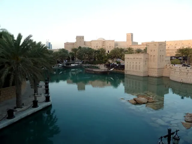 A water canal between buildings in local style with wind towers and palm trees