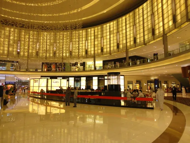 A luxury mall atrium with a gold lit wall, a polished marble floor and designer boutiques