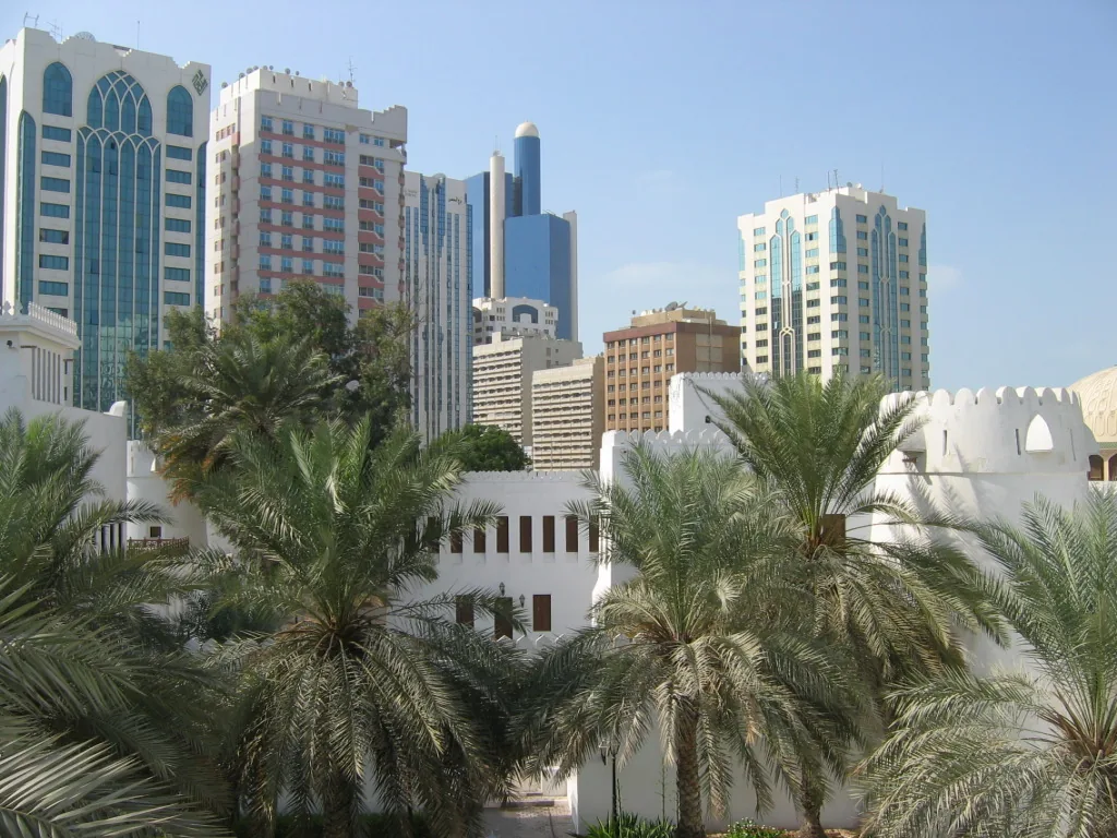 A low fort wall in the foreground, glass city towers rising above it