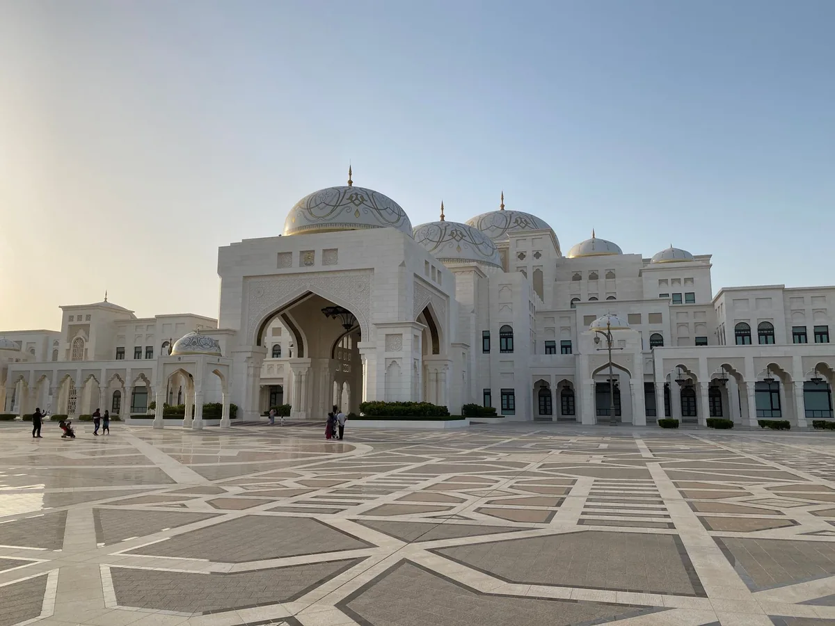 A white palace with domes and a patterned forecourt