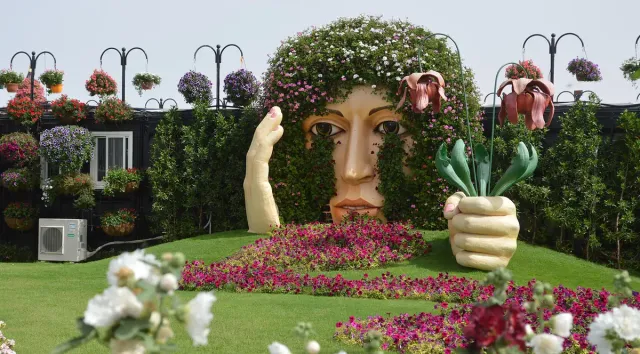 Large flower covered sculptures on a lawn between colourful flower beds