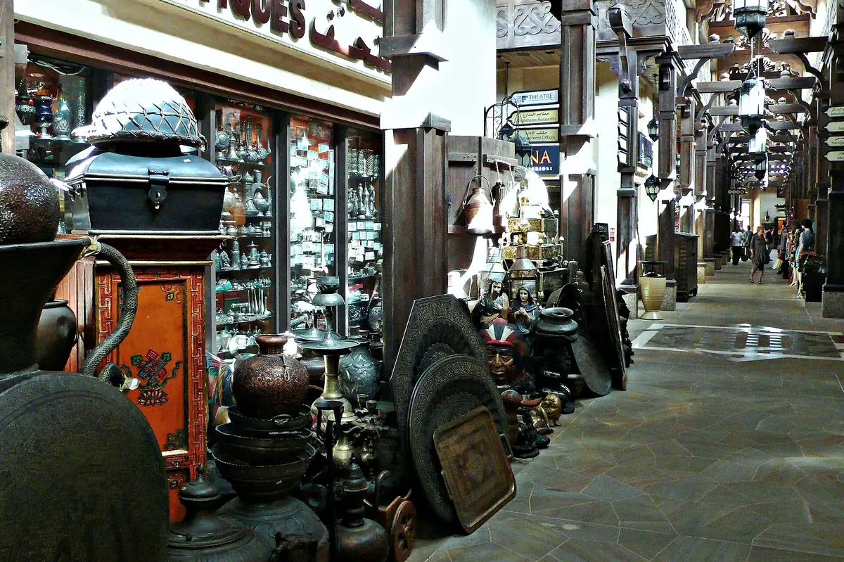 A covered souk corridor with lamps and copper wares