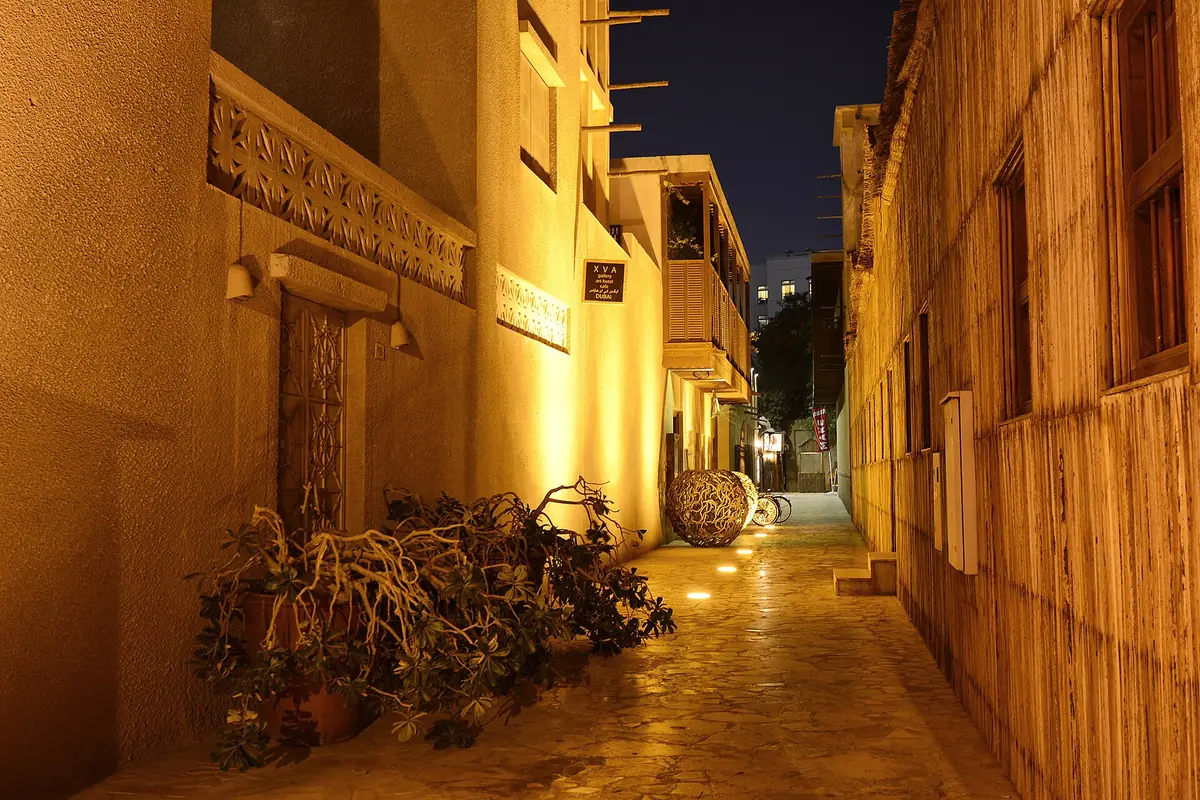 A lit lane between plastered walls in the evening