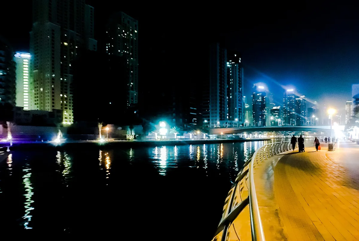 Lit marina towers seen over the water from a boat