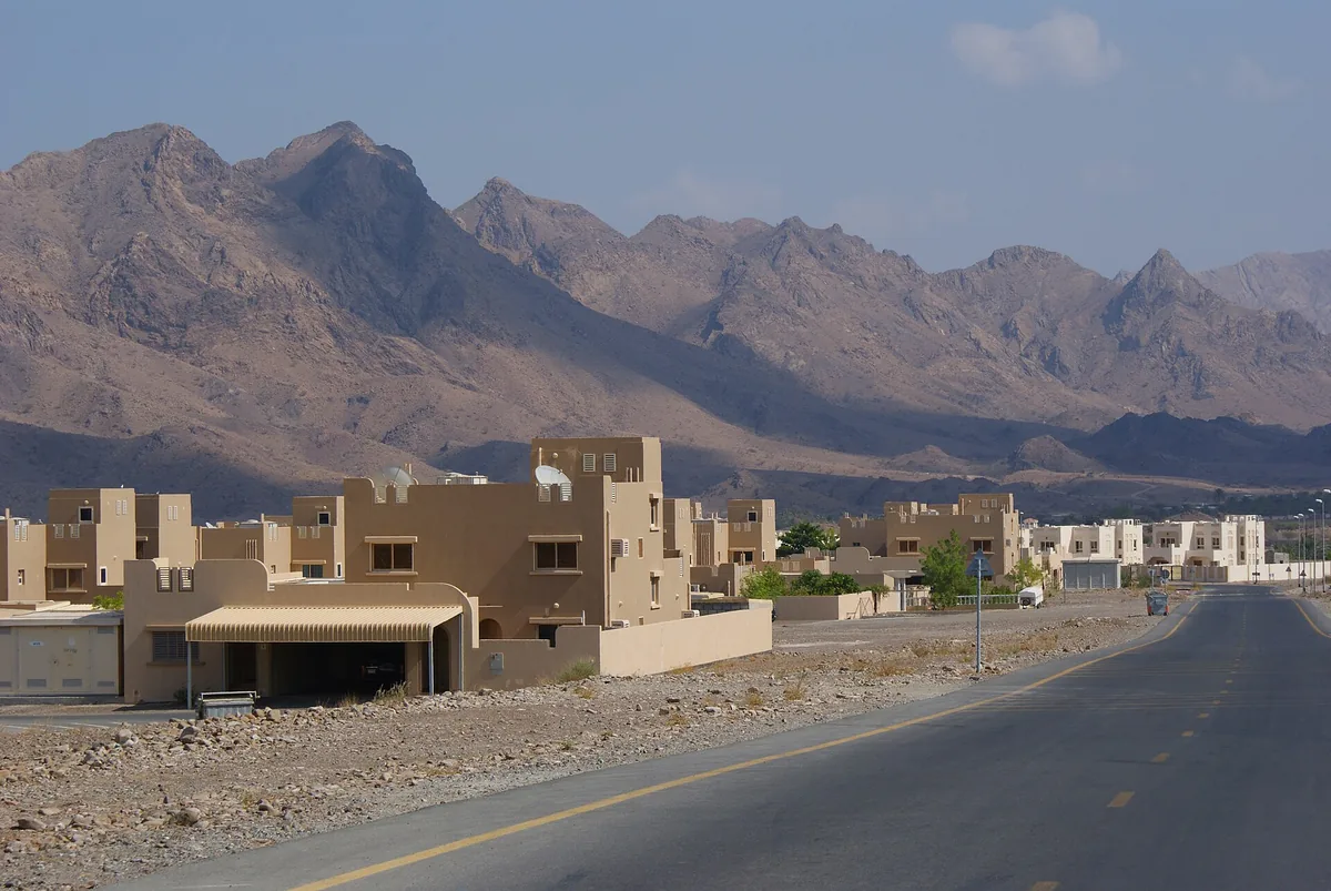 Bare mountains above a road and low buildings