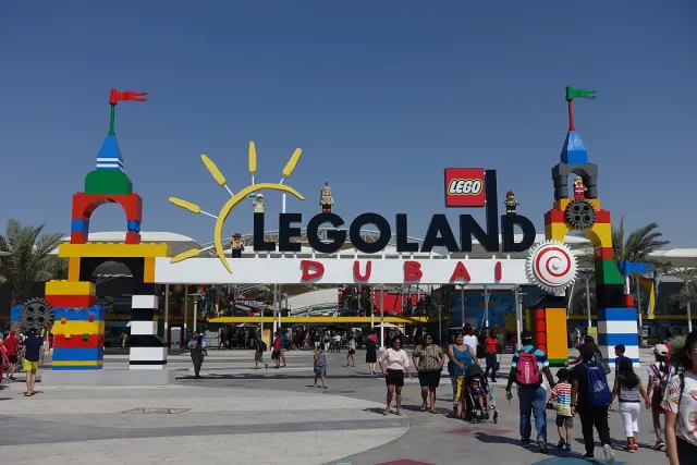 An entrance gate built of colourful bricks with visitors in daylight