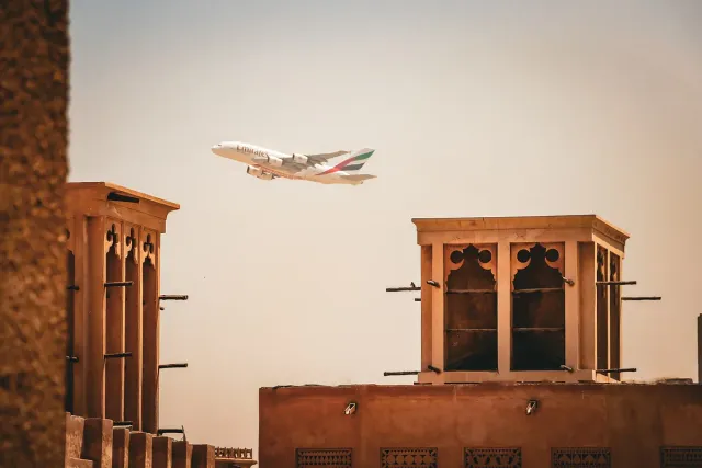 Plastered wind towers in warm light with an airliner climbing above them
