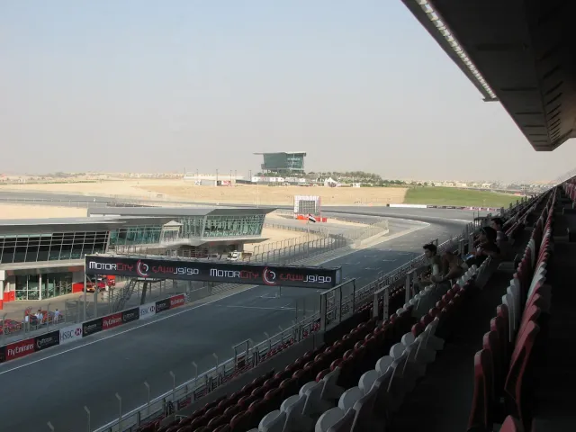 An empty race track with a finish line, grandstands and a control tower