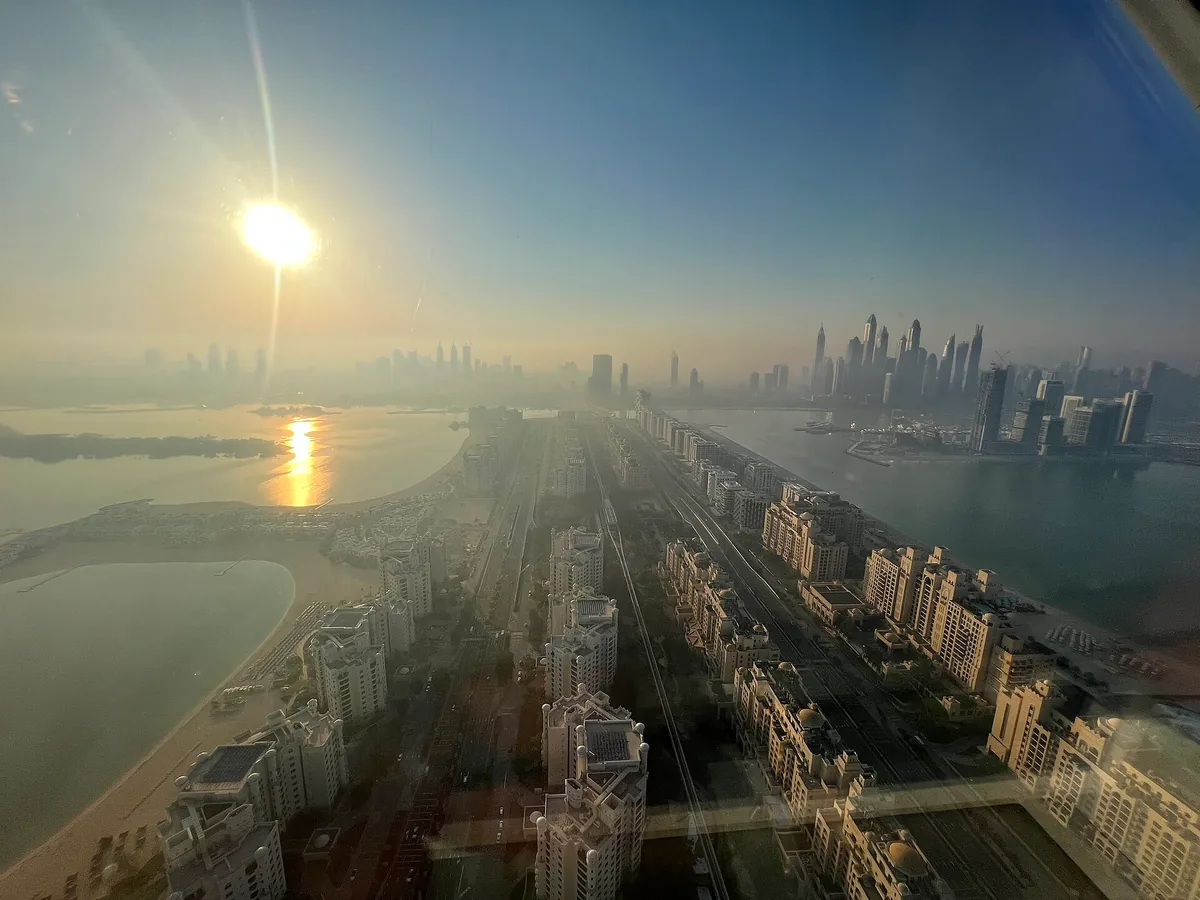 The view from the mall's rooftop observation deck, down the trunk of Palm Jumeirah towards the Dubai Marina skyline before sunset