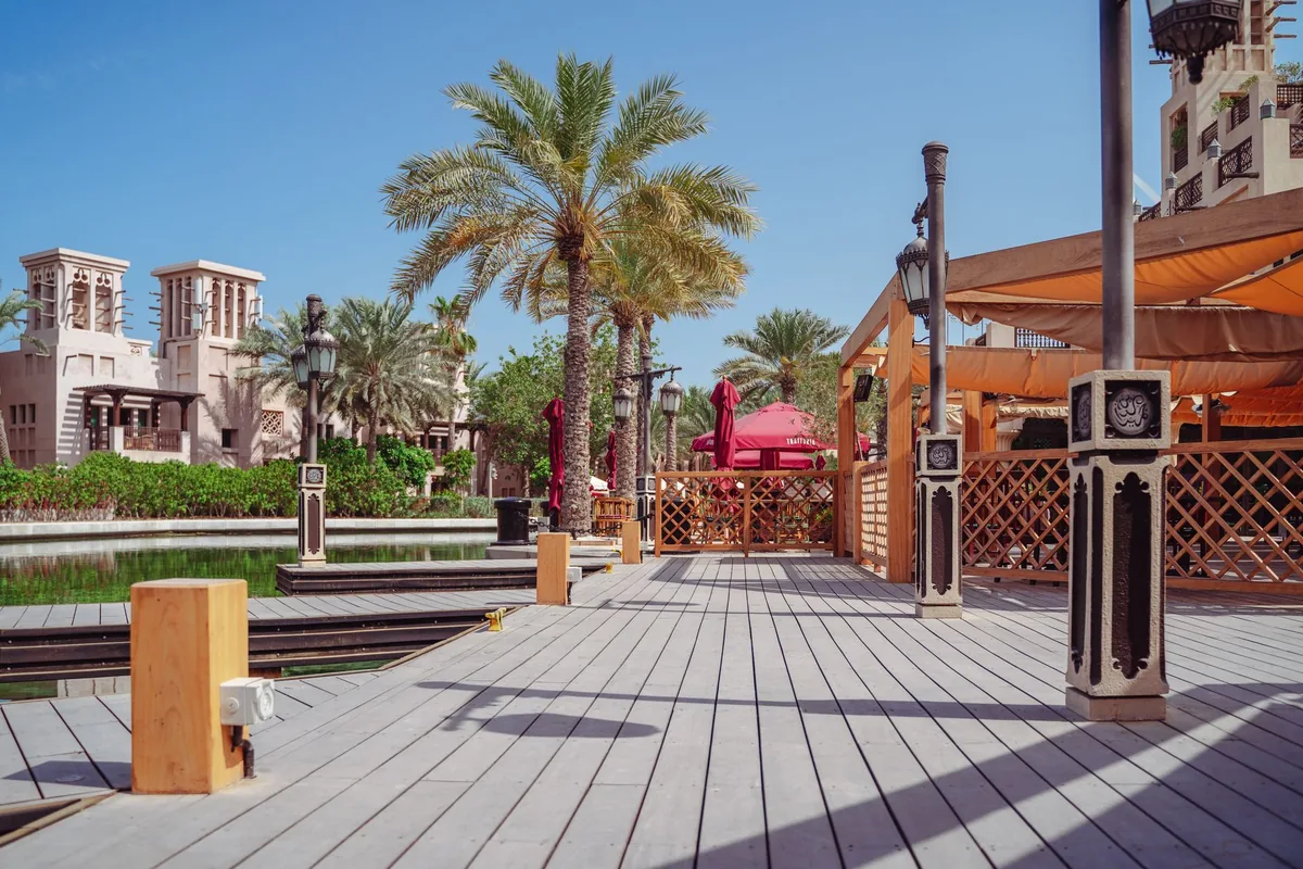 A wooden promenade with palms and wind towers