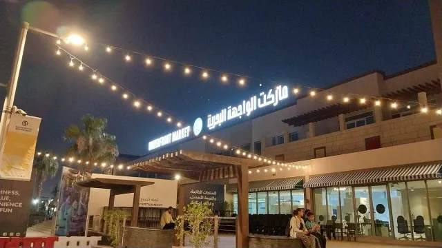 A market front lit by a glowing sign and strings of bulbs in the evening