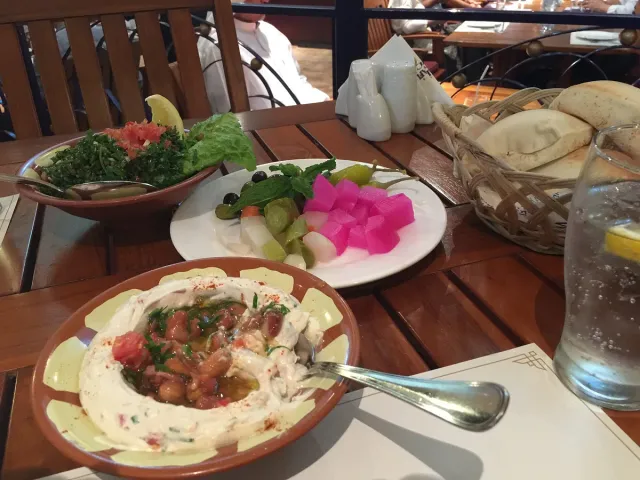 Lebanese mezze dishes on a wooden table beside salad and bread